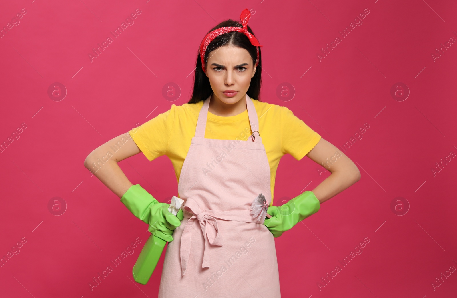 Photo of Emotional housewife with detergent and brush on pink background
