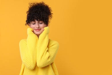 Photo of Young woman in stylish warm sweater on yellow background, space for text