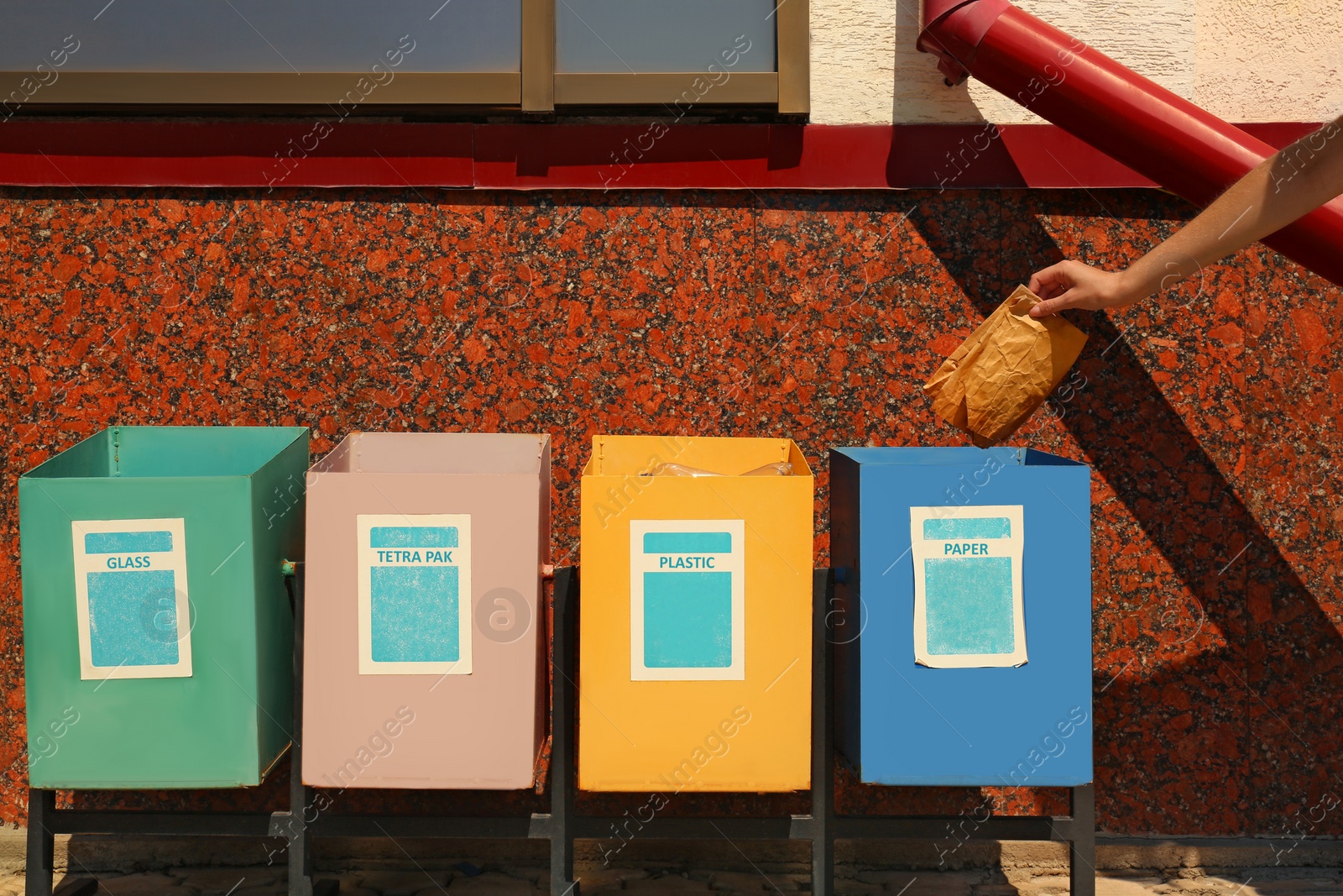 Photo of Woman throwing paper into recycling bin outdoors, closeup