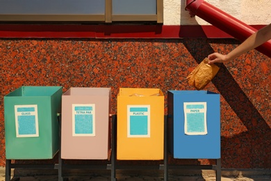 Photo of Woman throwing paper into recycling bin outdoors, closeup