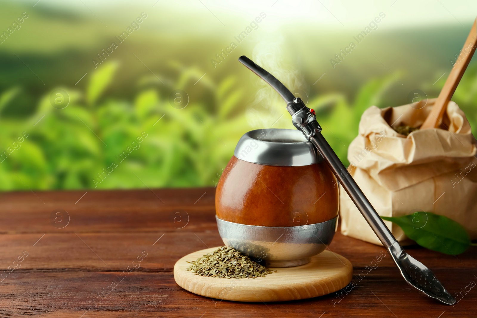 Image of Calabash with mate tea and bombilla on wooden table outdoors. Space for text