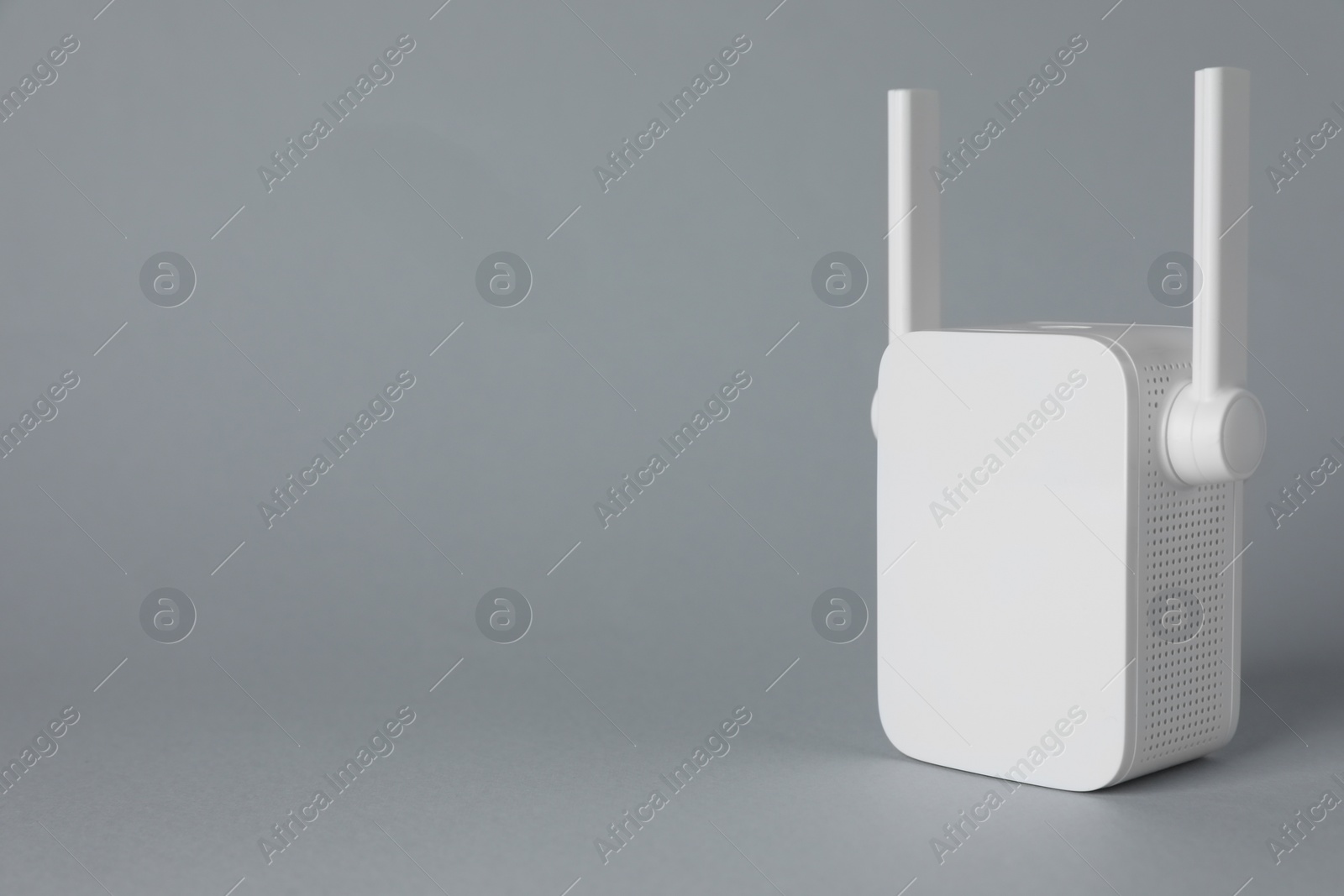 Photo of New modern Wi-Fi repeater on light gray background, space for text