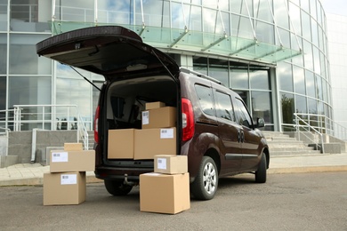 Photo of Courier car with packages parked near office building