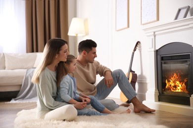 Photo of Happy family resting near fireplace at home