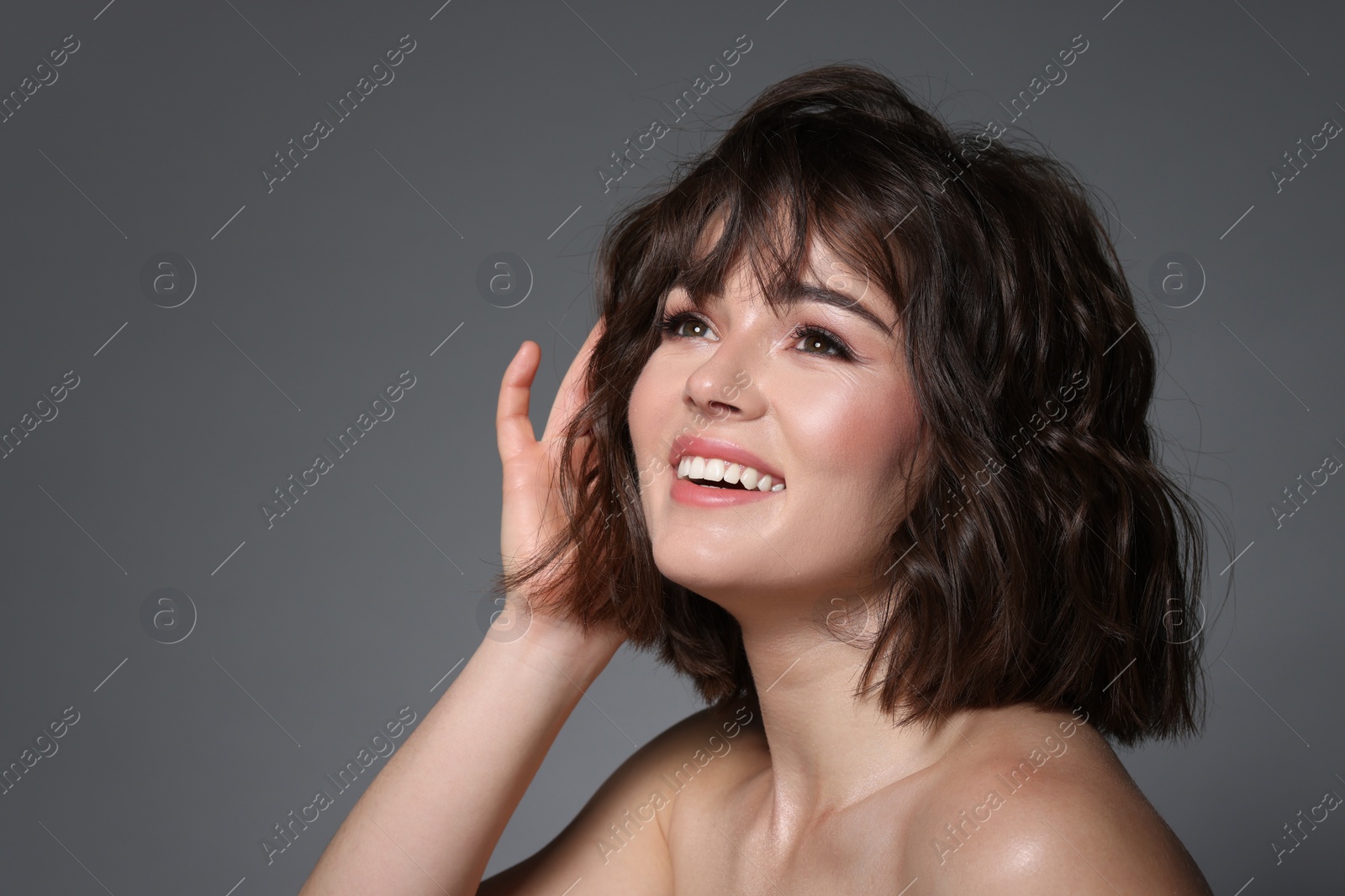 Photo of Portrait of beautiful young woman with wavy hairstyle on grey background. Space for text