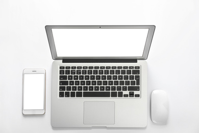 Modern laptop and smartphone on white background, top view