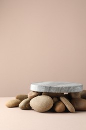 Photo of Presentation for product. Stone podium and pebbles on beige background. Space for text