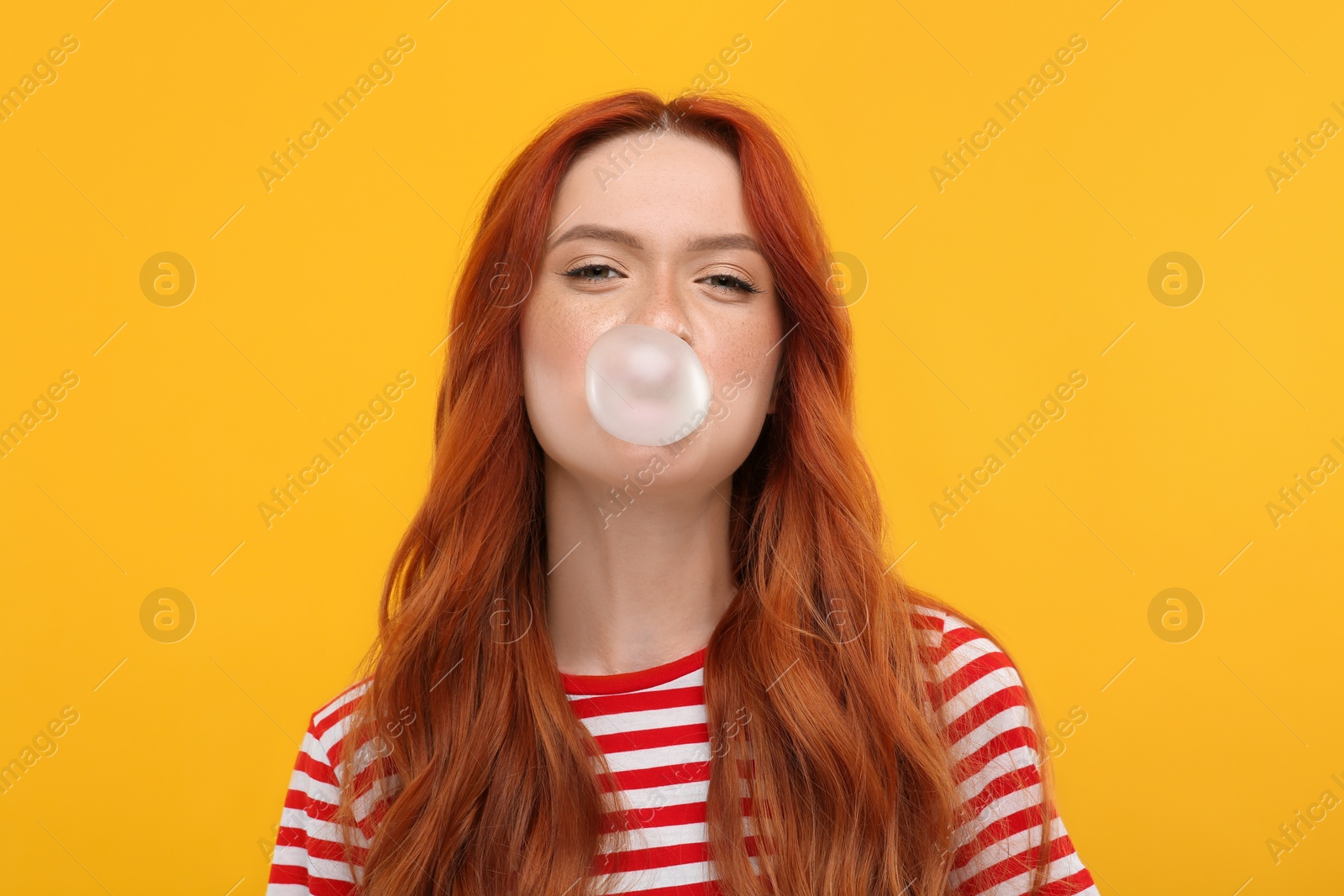 Photo of Portrait of beautiful woman blowing bubble gum on orange background