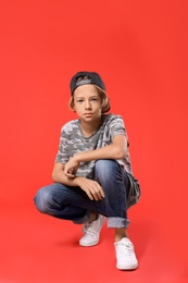 Photo of Cute little boy in casual outfit on red background