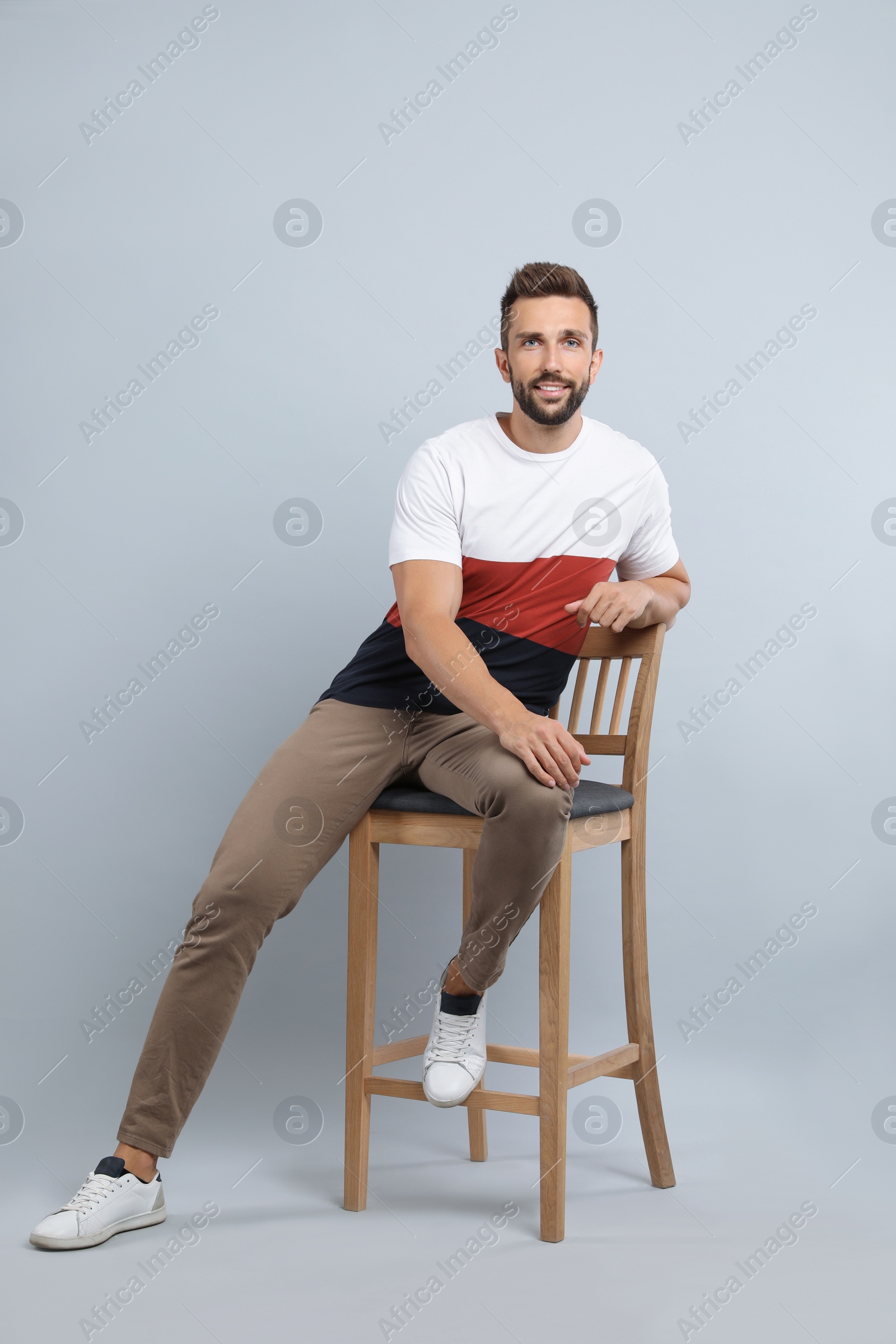 Photo of Handsome man sitting on stool against light grey background