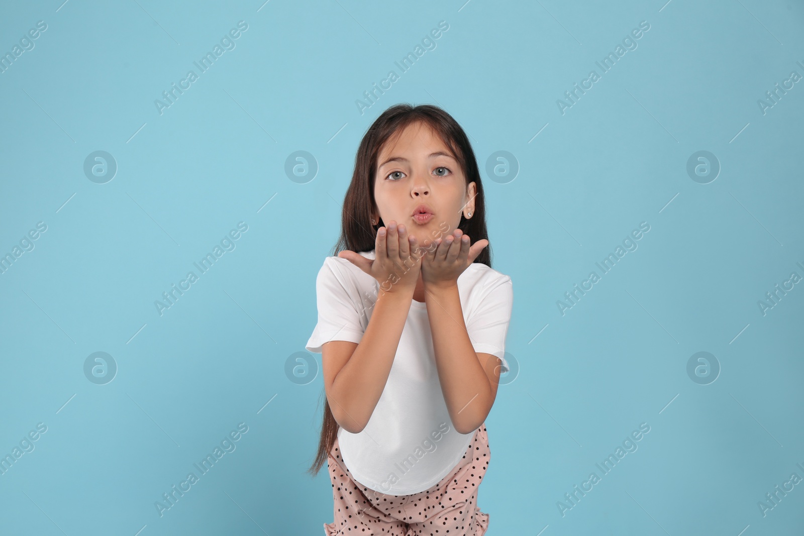Photo of Cute girl wearing pajamas on light blue background