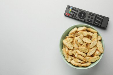 Photo of Remote control and rusks on light grey background, flat lay. Space for text