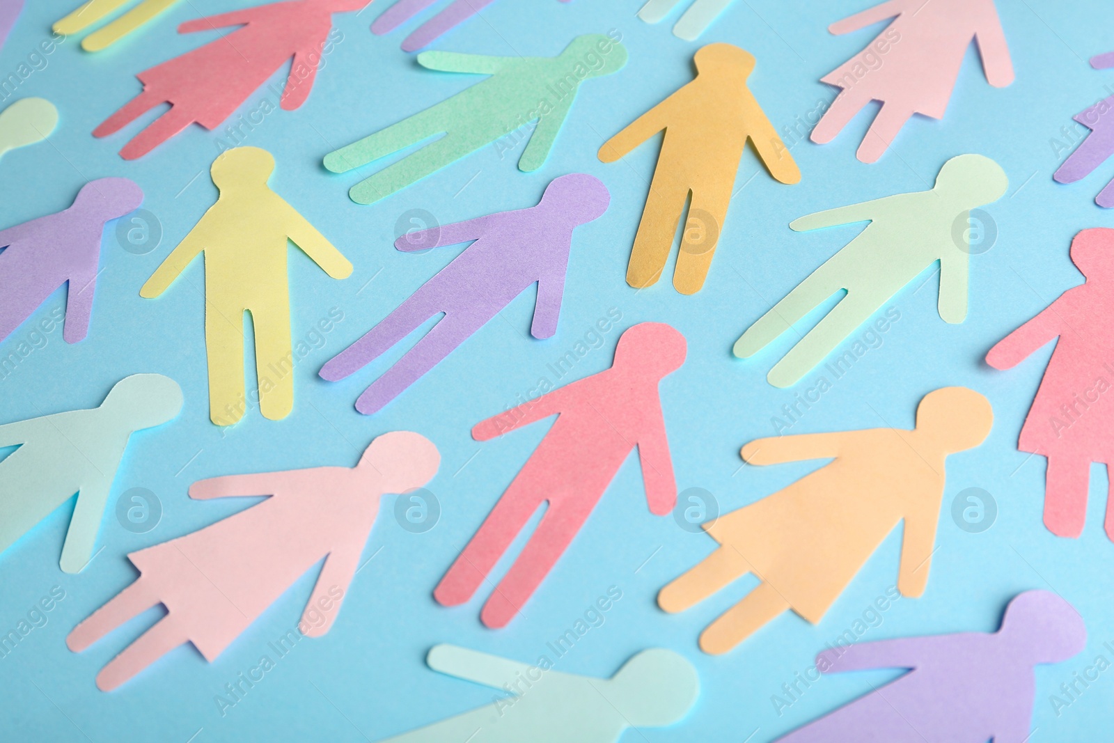 Photo of Many different paper human figures on light blue background. Diversity and inclusion concept