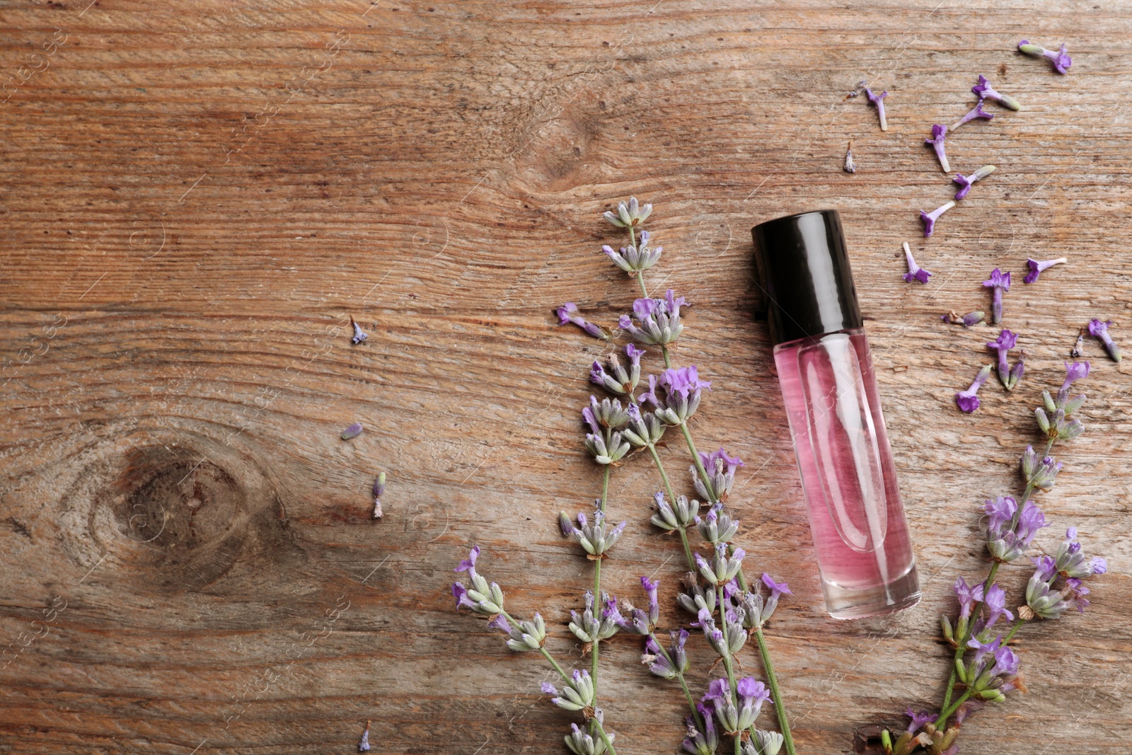 Photo of Flat lay composition with bottle of natural lavender essential oil on wooden background. Space for text