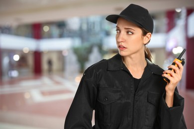 Image of Female security guard wearing uniform using portable radio transmitter in shopping mall