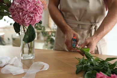Florist cutting flower stems at table, closeup