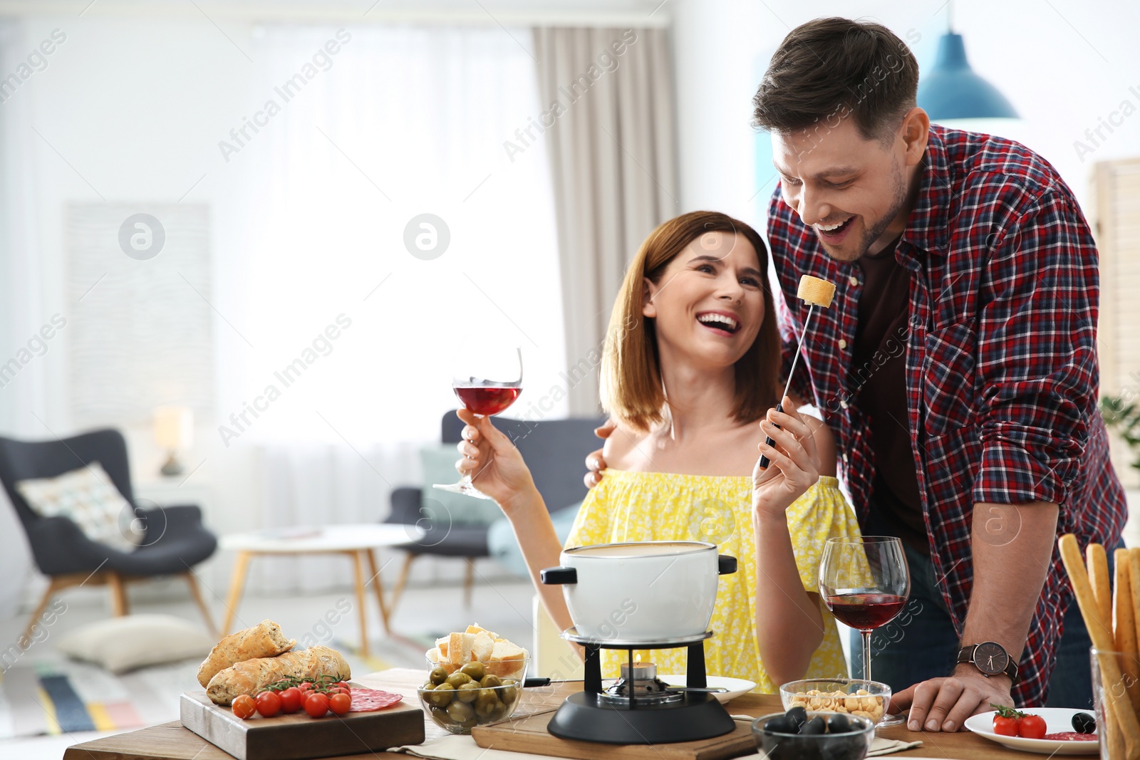 Photo of Happy couple enjoying fondue dinner at home