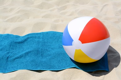 Blue towel and colorful beach ball on sand