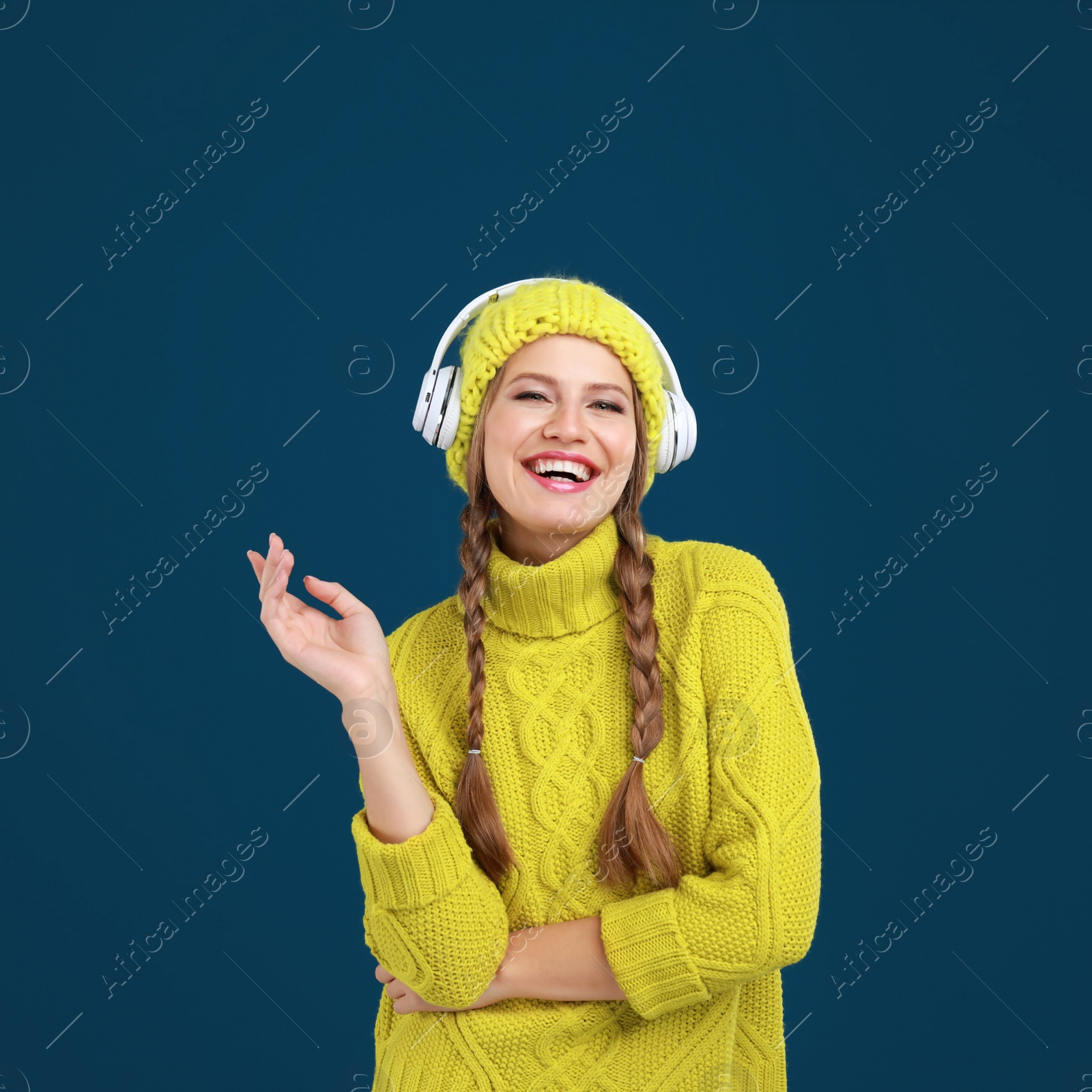 Photo of Young woman listening to music with headphones on dark blue background