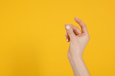 Photo of Woman snapping fingers on yellow background, closeup of hand. Space for text