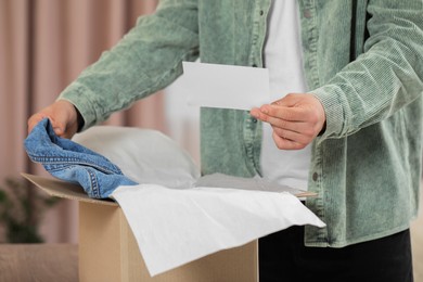 Man holding greeting card near parcel with Christmas gift, closeup