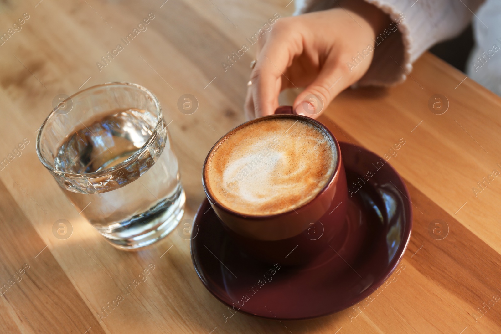 Photo of Woman with aromatic coffee at table in cafe, closeup