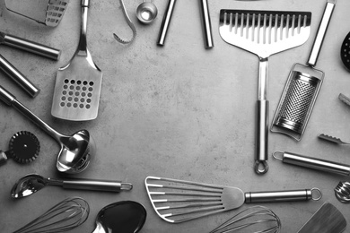 Flat lay composition with different kitchen utensils on grey background, space for text