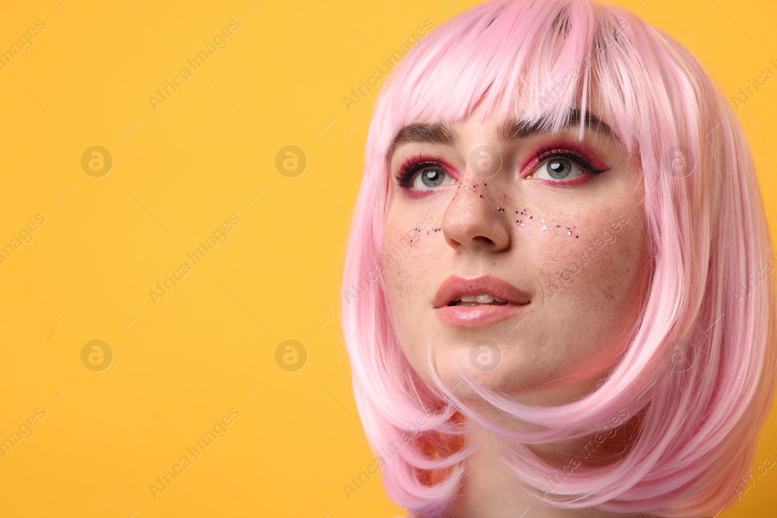 Photo of Beautiful woman with bright makeup and glitter freckles on yellow background. Space for text