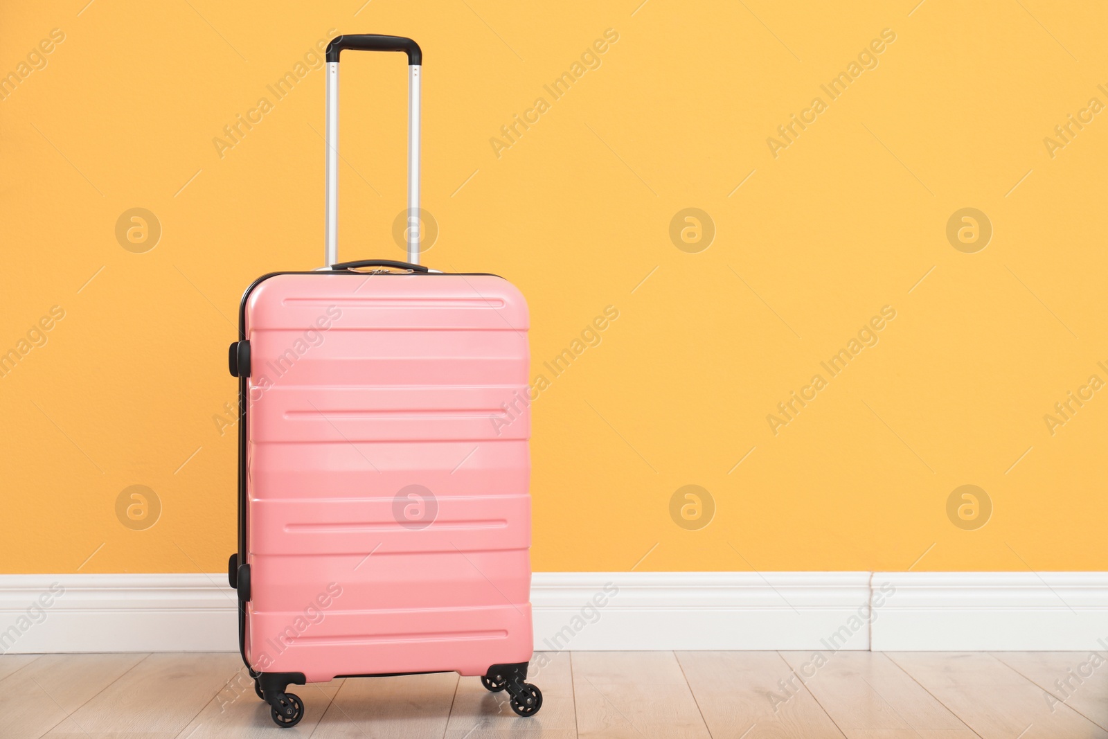 Photo of Suitcase packed for travel on floor near color wall. Space for text