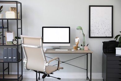 Photo of Comfortable office chair near desk with modern computer indoors