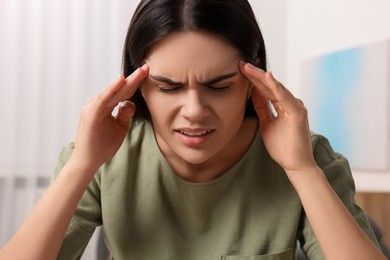 Sad woman suffering from headache at home