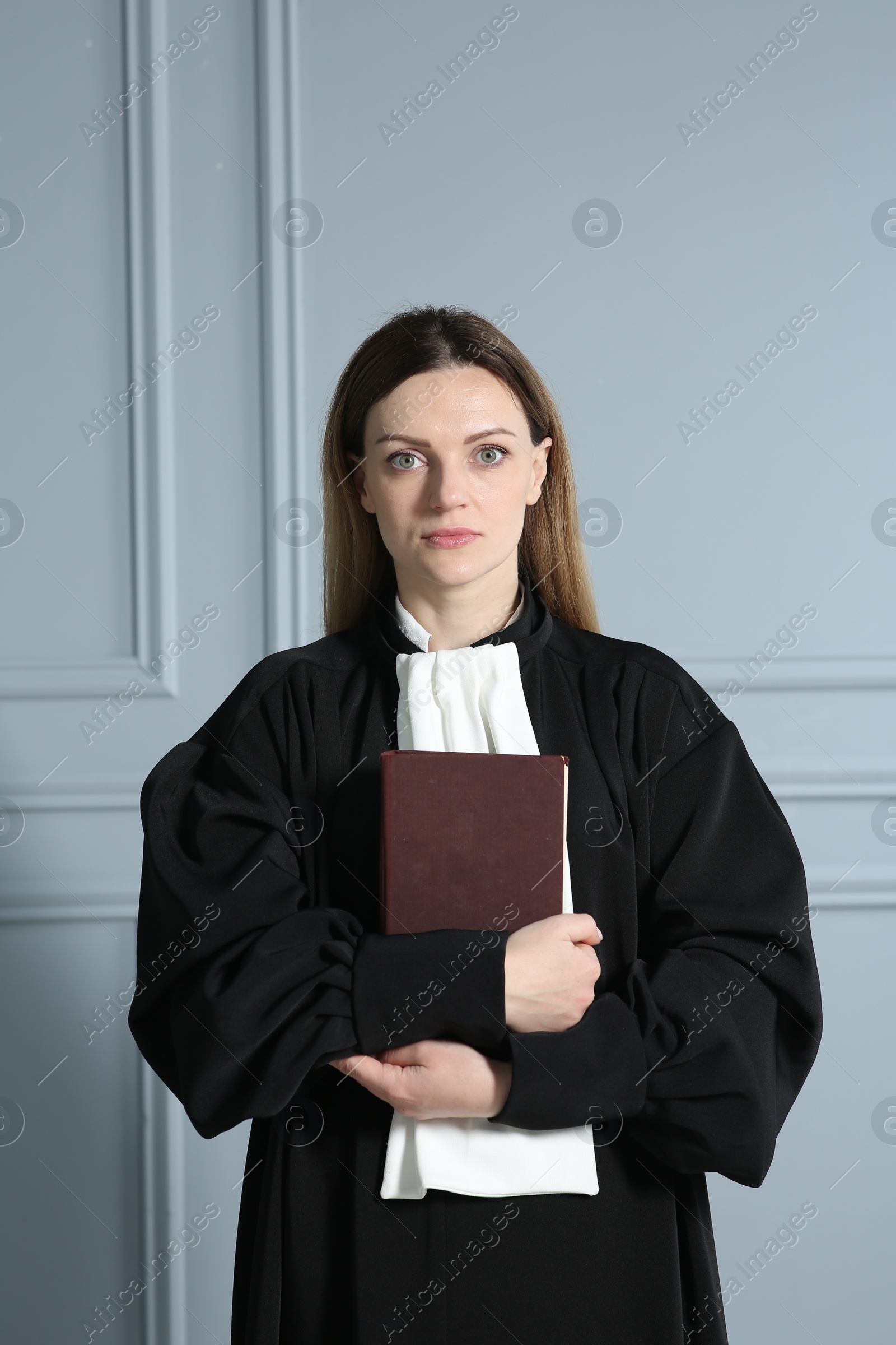 Photo of Portrait of judge with book near grey wall