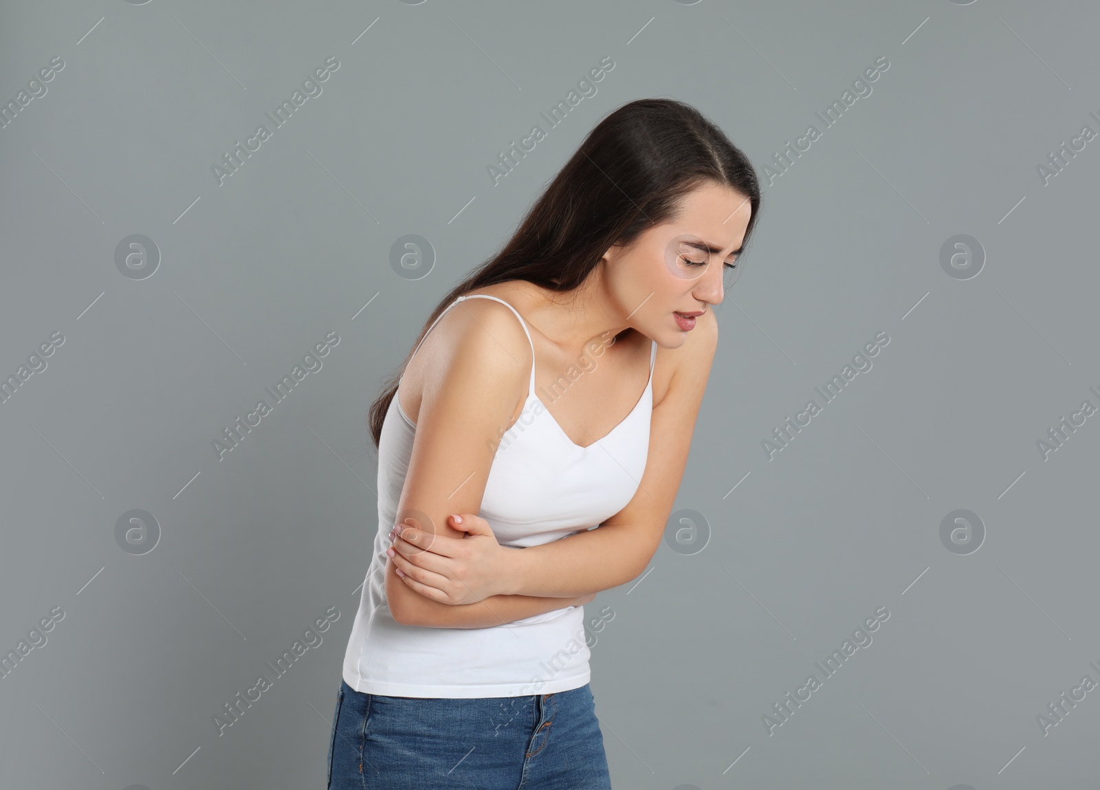 Photo of Young woman suffering from stomach ache on grey background. Food poisoning