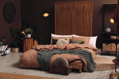 Stylish room interior with large bed near brown wall