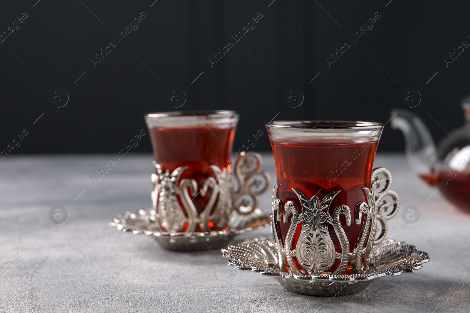 Photo of Glasses of traditional Turkish tea in vintage holders on light grey table