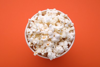 Photo of Bucket of tasty popcorn on orange background, top view