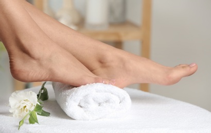 Woman with smooth feet on white towel indoors, closeup. Spa treatment