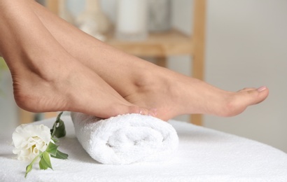 Photo of Woman with smooth feet on white towel indoors, closeup. Spa treatment