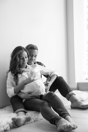 Photo of Pregnant woman with her husband indoors, black and white effect