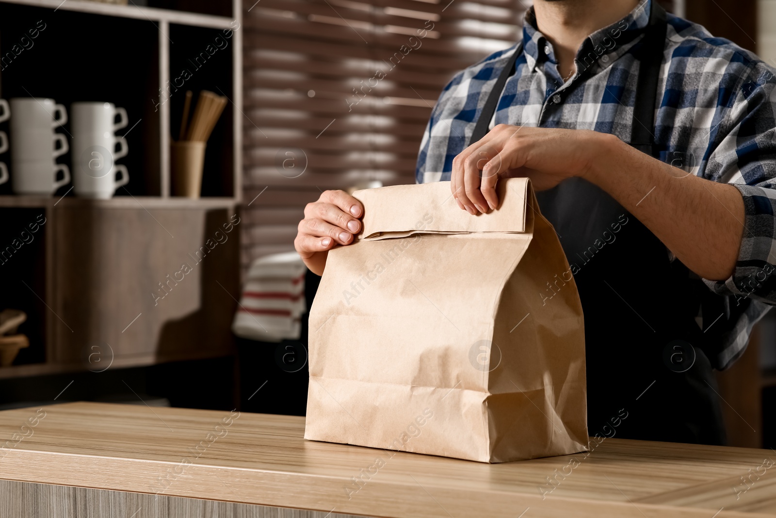 Photo of Worker with paper bag at counter in cafe, closeup. Space for text