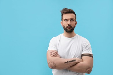 Image of Handsome man with beautiful tattoo sketches on turquoise background. Space for text