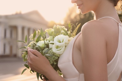 Photo of Bride in beautiful wedding dress with bouquet outdoors, closeup