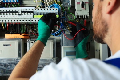 Photo of Electrician checking electric current with multimeter indoors, closeup