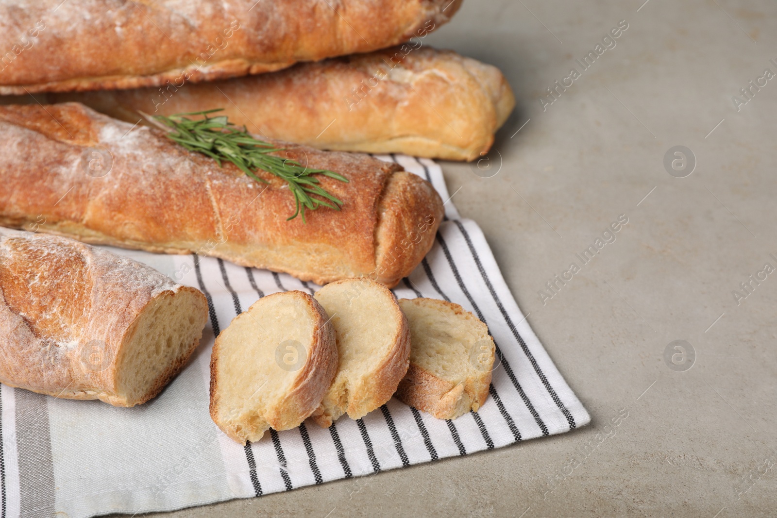 Photo of Fresh crispy baguettes on grey table, closeup. Space for text