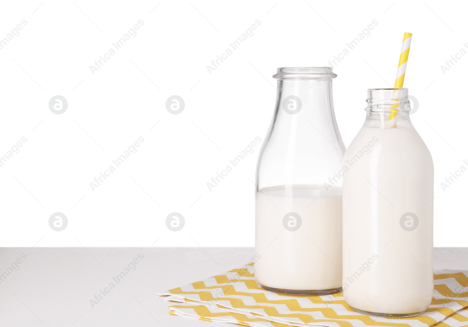 Photo of Bottles with tasty milk on light table against white background