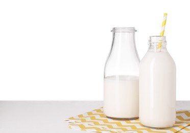 Bottles with tasty milk on light table against white background