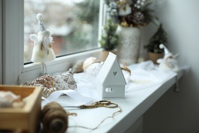 Photo of Christmas atmosphere. Beautiful decorative house, baubles and toys on window sill indoors