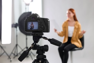 Photo of Casting call. Woman performing in front of camera against light grey background at studio, selective focus