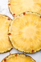 Slices of tasty ripe pineapple on white marble table, flat lay