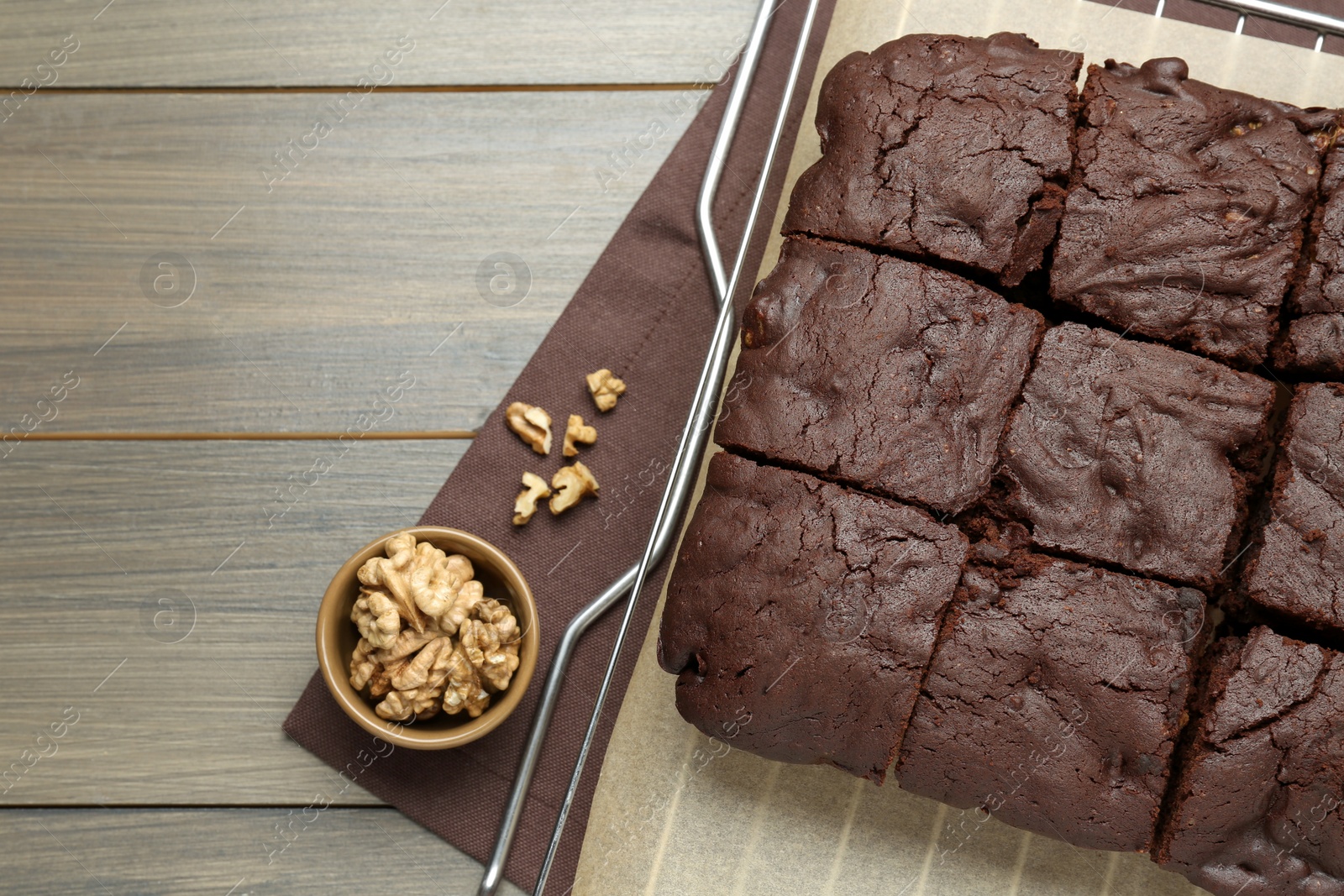 Photo of Delicious freshly baked brownies and walnuts on wooden table, flat lay. Space for text